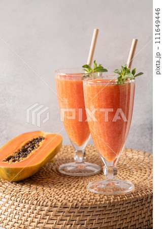 Two glasses of Papaya lassi, smoothie, juice on gray background. Freshness cold beverage of yogurt, water, spices, fruits and ice. Popular beverage in India and Sri lanka. Vertical format. 111649446