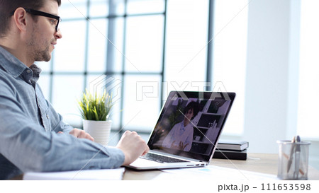 A male office worker at an online meeting with colleagues A male office worker at an online meeting with colleagues 111653598