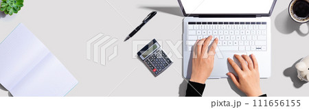 Woman using a laptop computer with a calculator 111656155
