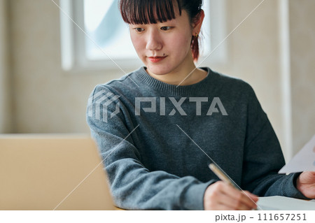 資料を持ちノートにメモをする若い女性 111657251