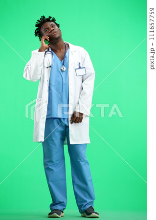 The doctor, in full height, on a green background, talking on the phone The doctor, in full height, on a green background, talking on the phone 111657759