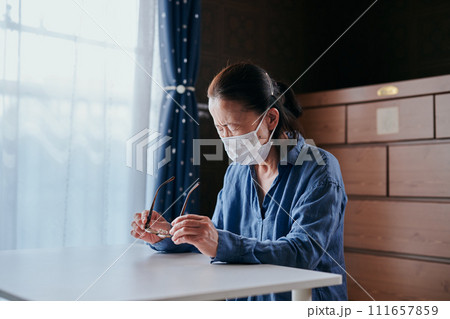 目が痛くてメガネを取り外す60代のシニア女性 111657859