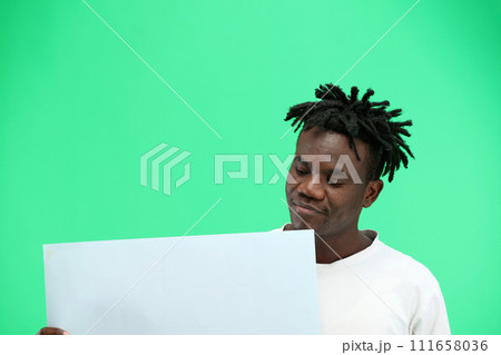 A man, close-up, on a green background, shows a white sheet 111658036