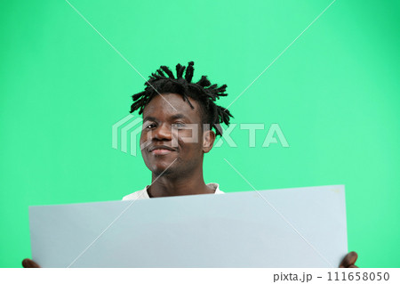A man, close-up, on a green background, shows a white sheet A man, close-up, on a green background, shows a white sheet 111658050