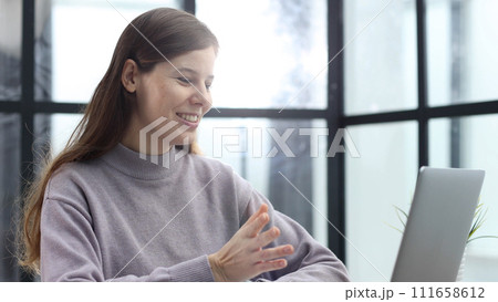 A woman in close-up at a desk in the office talking at an online video conference A woman in close-up at a desk in the office talking at an online video conference 111658612