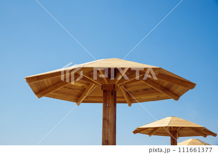 Beach wooden umbrella on blue sky. Beach canopy, sunshade or parasol. 111661377