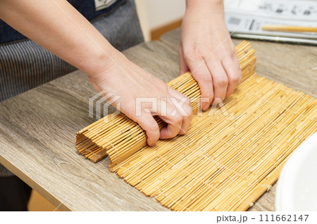 巻きすで巻き寿司を作る女性の手元 111662147