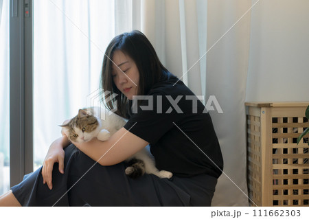 wellness and wellbeing concept with asian woman sit and play with her cat in livingroom 111662303