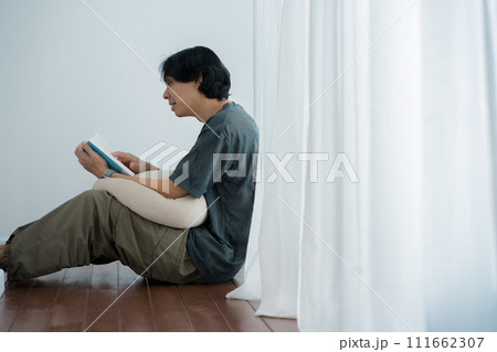 wellness and wellbeing concept with asian man sit and relax and read in livingroom 111662307
