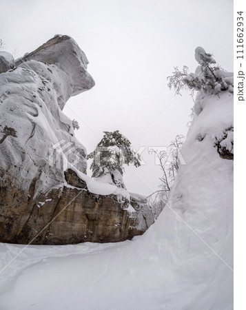Large stone cliff covered with frozen snow, view from below. Large stone cliff covered with frozen snow, view from below. 111662934