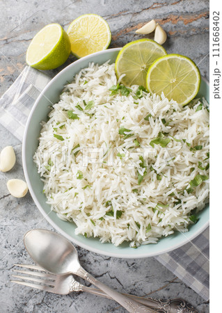Cilantro Garlic Rice with lime zest and juice closeup on the bowl on the marble table. Vertical top view 111668402