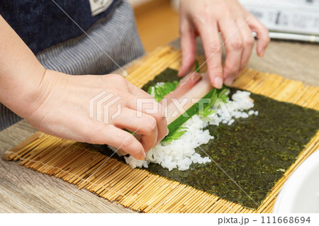 巻きすで巻き寿司を作る女性の手元 巻きすで巻き寿司を作る女性の手元 111668694