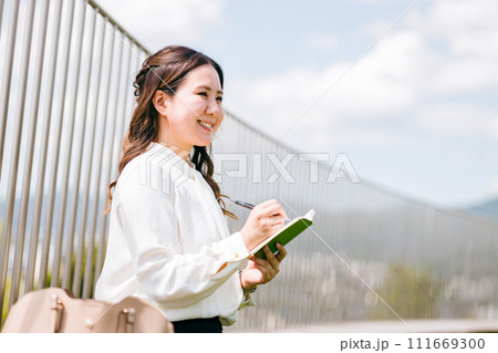 屋上で取材するマスコミの女性（インタビュアー・記者・ビジネスウーマン・ジャーナリスト・ライター） 111669300