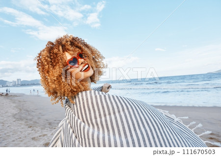 Summer Beach Freedom: Smiling Woman Embracing Nature's Close-Up Bliss with Curly Hair and Freckles, Expressing Joy while Listening to Music in Headphones of Happiness - Outdoors Summer Beach Freedom: Smiling Woman Embracing Nature's Close-Up Bliss with Curly Hair and Freckles, Expressing Joy while Listening to Music in Headphones of Happiness - Outdoors 111670503