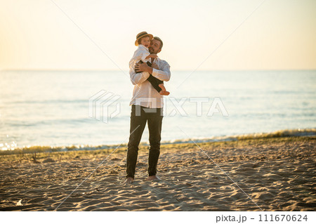 Father holding his happy baby girl at the sand beach of the Baltic Sea. Father holding his happy baby girl at the sand beach of the Baltic Sea. 111670624