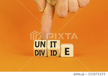 Unite or divide symbol. Concept word Unite or Divide on wooden cubes. Beautiful orange table orange background. Businessman hand. Business unite or divide concept. Copy space. 111671255