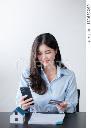 Beautiful Asian woman with smart phone and credit card, she fills in credit card information to pay for goods and services, online shopping concept pay by credit card via smartphone. 111672260