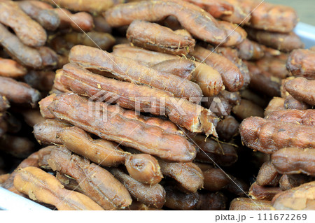 Tropical tamarind fruit without a shell, with visible seeds and inner pulp, in a galvanized tray on a wooden. Concept of food preservation in Thai style. Peeled tamarind is a ready-to-eat concept. 111672269