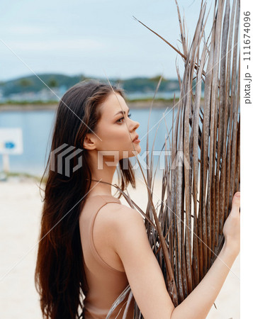 Summer Beauty: A Young Attractive Lady with Brunette Hair Posing in a Stylish White Dress on the Sunny Beach Summer Beauty: A Young Attractive Lady with Brunette Hair Posing in a Stylish White Dress on the Sunny Beach 111674096