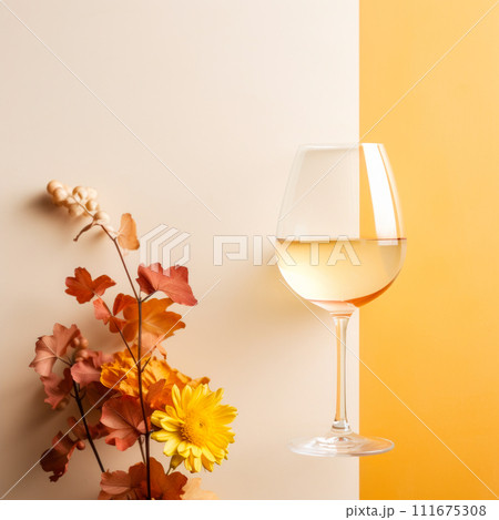 Glass of white wine and autumn leaves on stand near yellow wall with copy space on table creating elegant scene 111675308