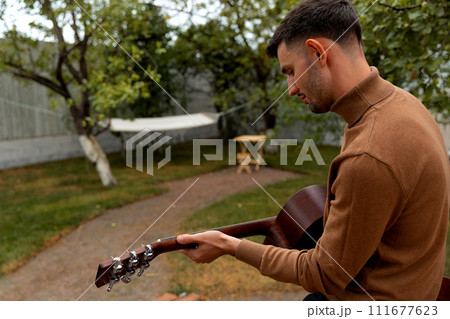 young man sits at the table and plays the guitar young man sits at the table and plays the guitar 111677623
