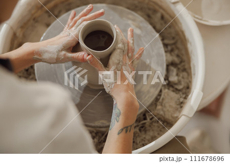 Close up of hands of professional potter molding pot shape on pottery wheel. Ceramics art concept Close up of hands of professional potter molding pot shape on pottery wheel. Ceramics art concept 111678696