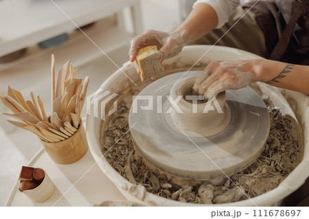 Close up of hands of professional potter molding pot shape on pottery wheel. Ceramics art concept Close up of hands of professional potter molding pot shape on pottery wheel. Ceramics art concept 111678697
