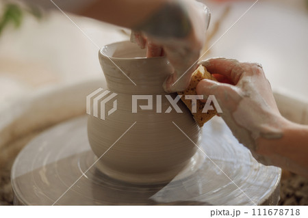 Close up of hands of professional potter molding pot shape on pottery wheel. Ceramics art concept Close up of hands of professional potter molding pot shape on pottery wheel. Ceramics art concept 111678718