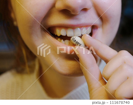 oval white tablet with the inscription happy in the mouth of a teenager 111678740