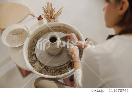 Close up of artisan's hands shaping clay bowl in pottery studio. Pottery art and creativity 111678743