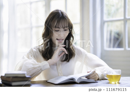 日差しが差し込む明るい部屋で読書する女性 日差しが差し込む明るい部屋で読書する女性 111679115