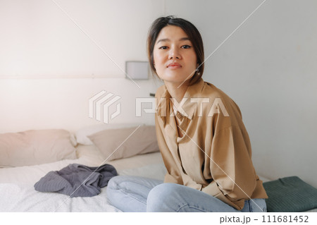 Asian woman sit on the bed in a small bedroom of budget hotel. Asian woman sit on the bed in a small bedroom of budget hotel. 111681452