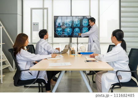 Group of doctor in white gown, discussing brain scans on large monitor in a meeting room. 111682485