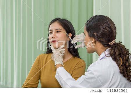 Doctor giving female patient medical injection in temporal. Atmosphere at cosmetic surgery department in hospital clinic. Doctor giving female patient medical injection in temporal. Atmosphere at cosmetic surgery department in hospital clinic. 111682565