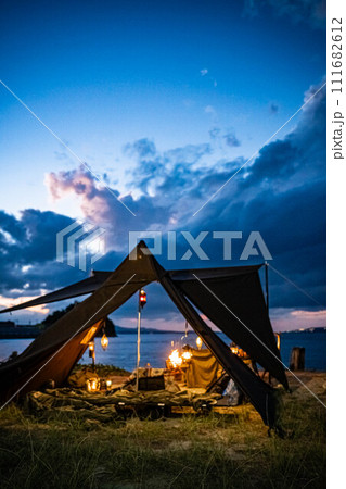 テント設営 夜キャンプ ランプ 焚き火 ランタン 神秘的 夕暮れ 111682612