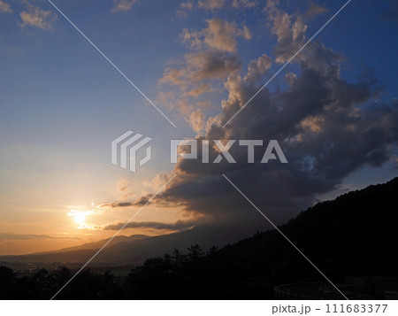 初夏の夕暮れ時、磐梯山に重なった積乱雲が夕日でオレンジ色に染まり、青空に印象的で綺麗だ。 初夏の夕暮れ時、磐梯山に重なった積乱雲が夕日でオレンジ色に染まり、青空に印象的で綺麗だ。 111683377