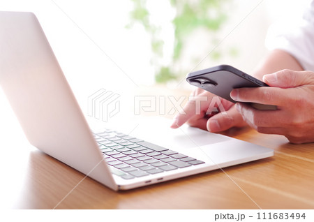 パソコンとスマホを操作する男性 パソコンとスマホを操作する男性 111683494
