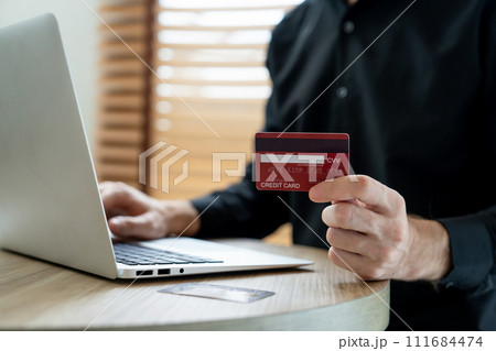 Young man using laptop with credit card for internet banking. Unveiling 111684474