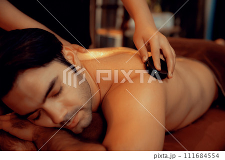 Hot stone massage at spa salon in luxury resort with warm candle light.Quiescent Hot stone massage at spa salon in luxury resort with warm candle light.Quiescent 111684554