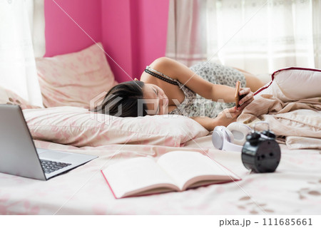 young Asian woman lying on bed and use smart phone during break young Asian woman lying on bed and use smart phone during break 111685661