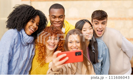Diverse teenager people taking a selfie smiling and laughing outdoors 111686043