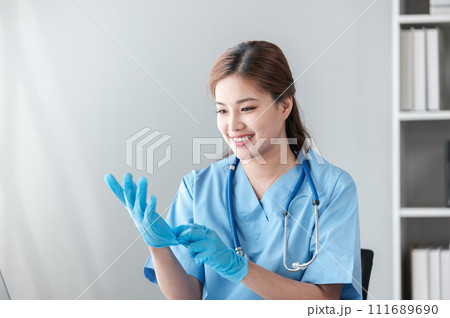 Young hispanic woman wearing doctor uniform wearing gloves at clinic 111689690