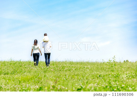 青空の草原を散歩する家族 111690306