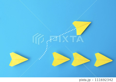 Top view of yellow paper airplanes with one flying at different direction Top view of yellow paper airplanes with one flying at different direction 111692342