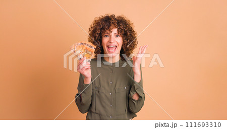 Cheerful woman showing Euro banknotes in beige studio 111693310