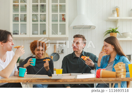 Home party. Overjoyed diverse friends eating ordered pizza for home party. Happy group mixed race young buddies enjoying spending free weekend time together having fun laughing joking communicating 111693518