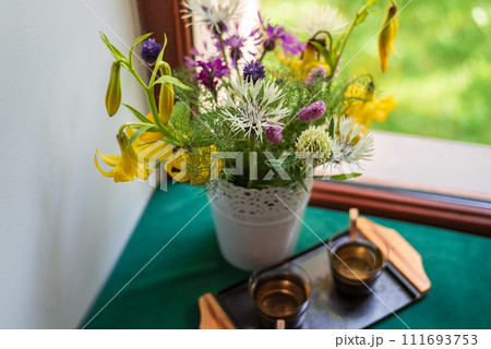 Bouquet of field yellow lilies and lilac, white cornflowers in a white pot on the windowsill Bouquet of field yellow lilies and lilac, white cornflowers in a white pot on the windowsill 111693753