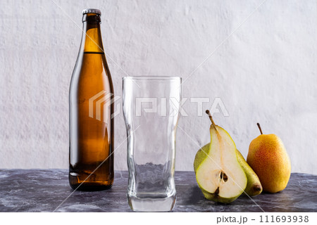 Empty glass near bottle and pear. A slice of pear and a glass. Empty glass near bottle and pear. A slice of pear and a glass. 111693938
