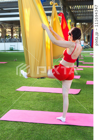 Woman in red sportswear doing gymnastics on fabrics 111694347