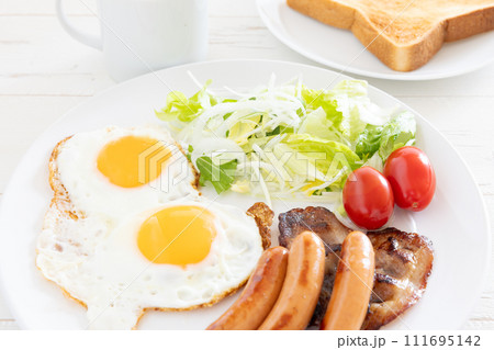 朝食の美味しい目玉焼きとソーセージとベーコンと野菜サラダ 111695142
